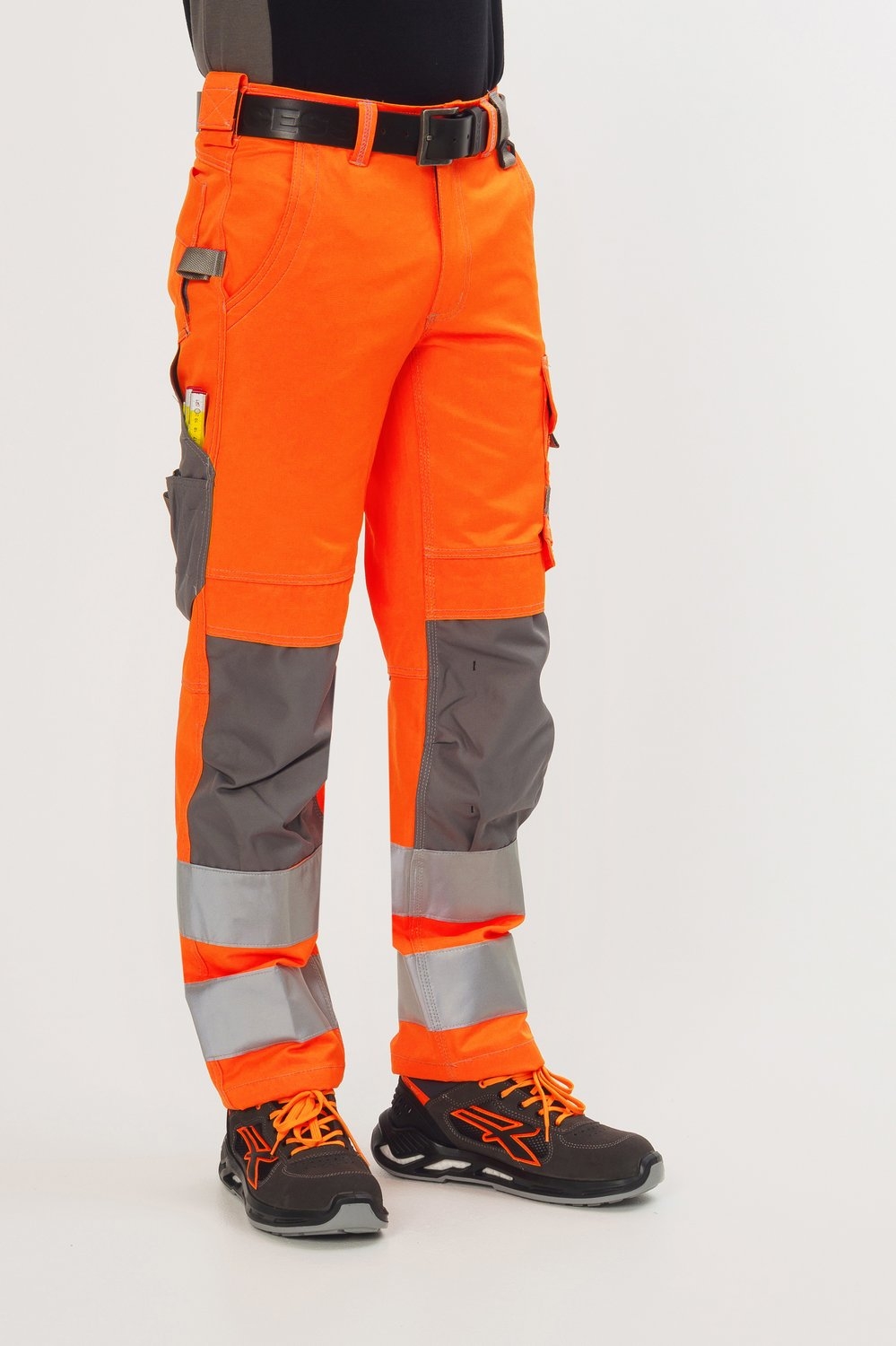 Orange Bundhose mit silbernen Reflexstreifen, grauen Einsätzen, Multifunktionstaschen und schwarzen Sicherheitsschuhen.