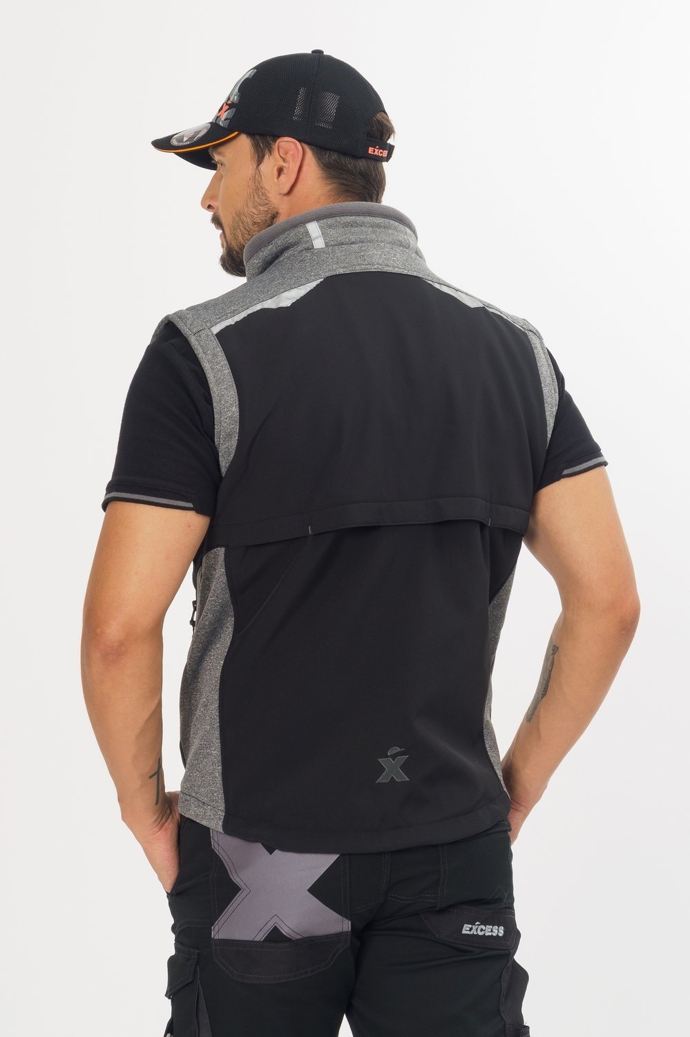Rückseite der ärmellosen Softshell-Arbeitsweste von Excess in Schwarz mit grauen Einsätzen, Belüftungsfalte am Rücken und reflektierendem Logo am Saum, getragen am Modell.