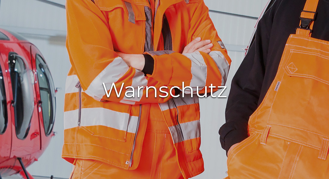 Zwei Personen in orangefarbener Warnschutzkleidung mit reflektierenden Streifen stehen vor einem roten Hubschrauber. In der Bildmitte steht der Schriftzug „Warnschutz“.