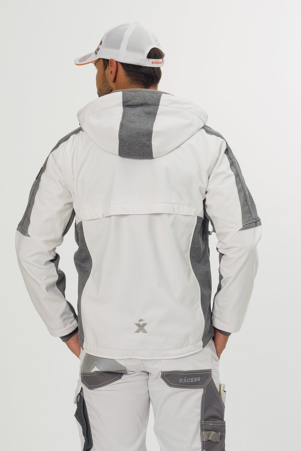 Rückansicht einer weißen Softshelljacke von Excess Workwear mit grauen Einsätzen, verstellbarer Kapuze, Logo am unteren Rücken und ergonomischem Schnitt. Getragen mit passender weiß-grauer Arbeitshose, ideal für Outdoor und Arbeit.