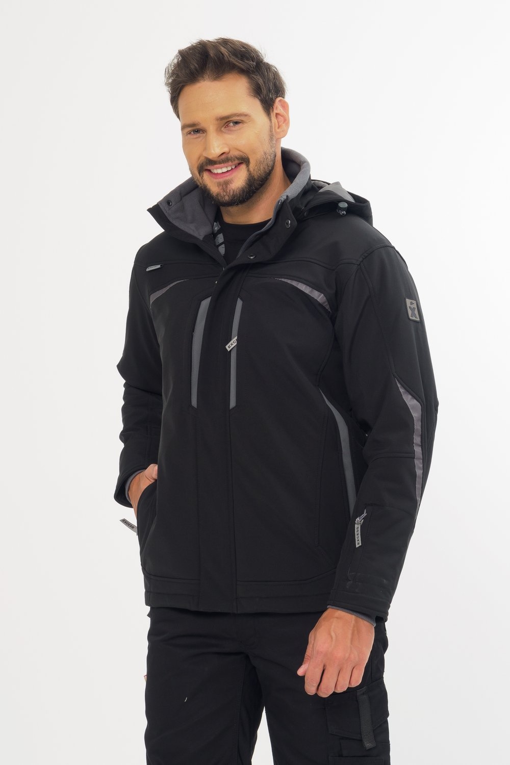 Excess Workwear Softshelljacke in Schwarz mit Kapuze, Reflexdetails, grauen Einsätzen und Reißverschlusstaschen, getragen am Modell.